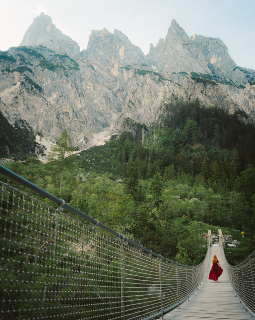 girl in a red dress walking along a Suspension Bridge Reiter Alpe Mountains Klausbachtal