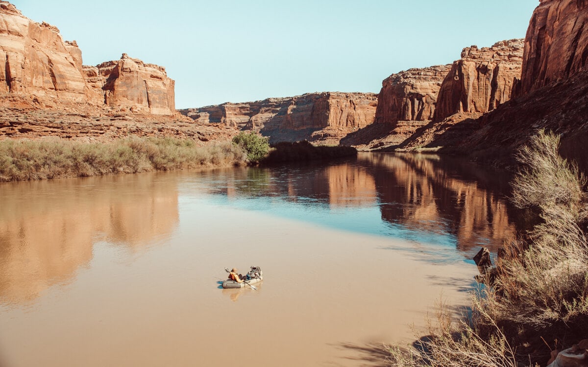 female in a packraft floating down the green river in canyonlands national park utah