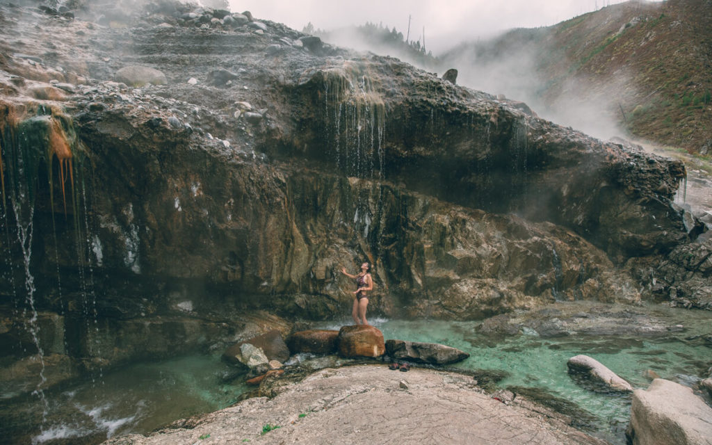 girl standing in the blue water in kirkham hot springs idaho
