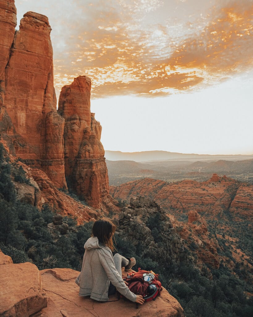 female hiker at the cathedral rock vista watching sunset