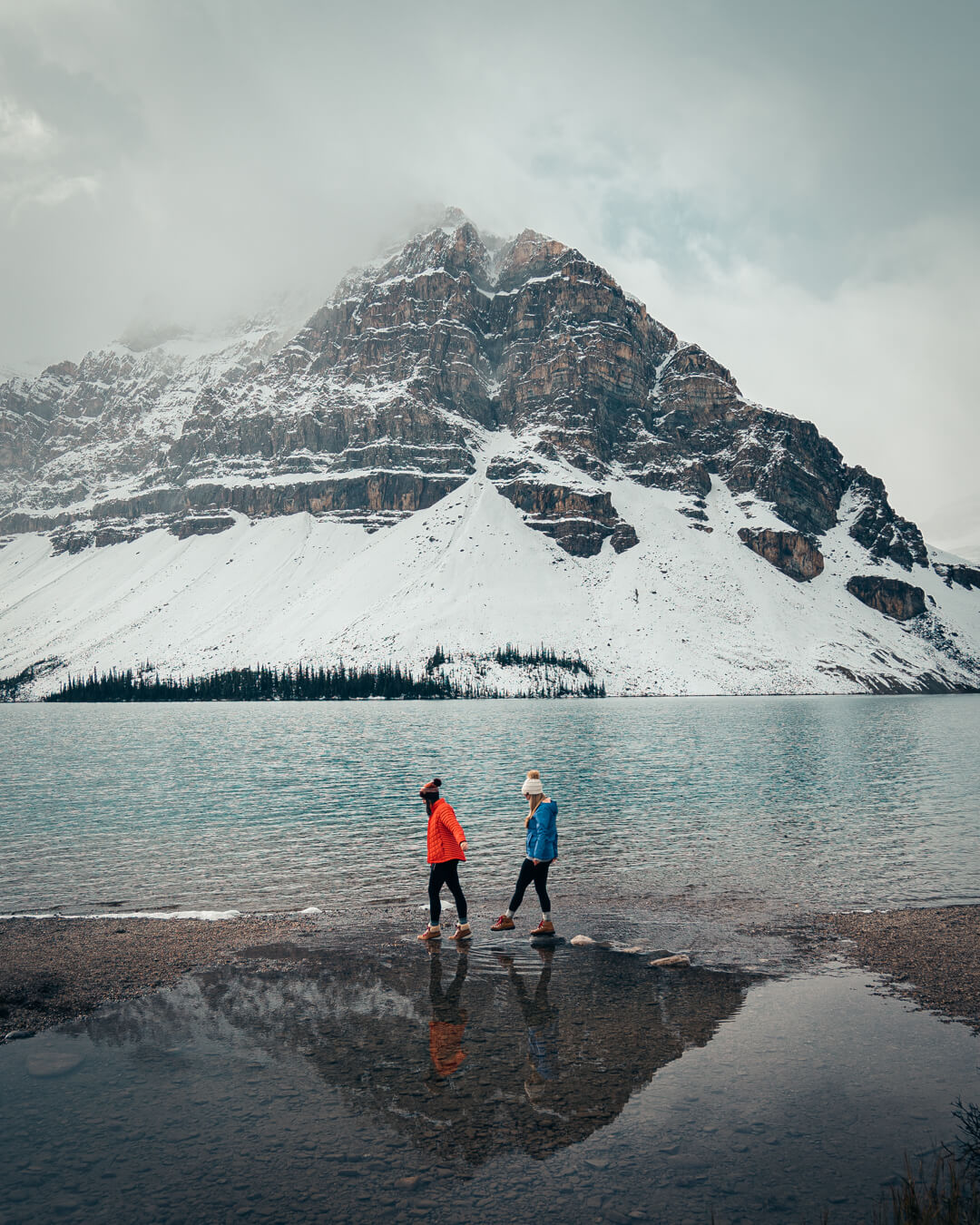 two female hikers walking around bow lake in winter