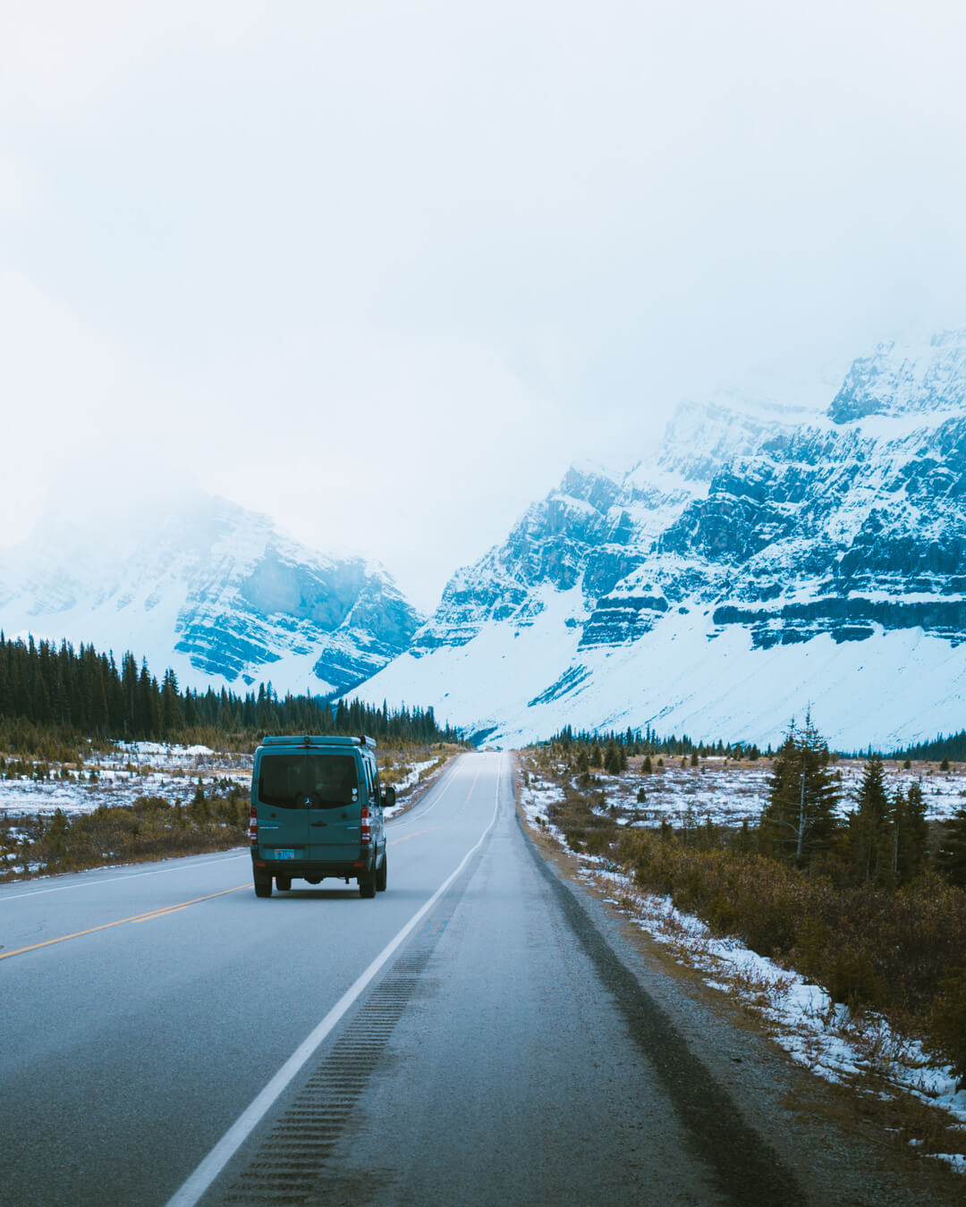 green campervan driving through icefields parkway in banff