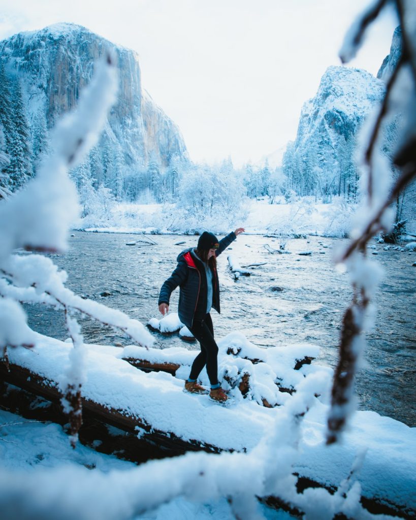 girl walking on a snow covered log in yosemite national park winter