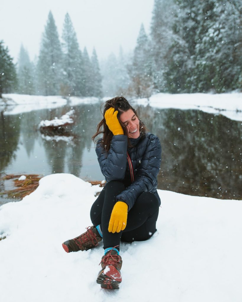 girl wearing yellow gloves, sitting in snow in Yosemite National Park