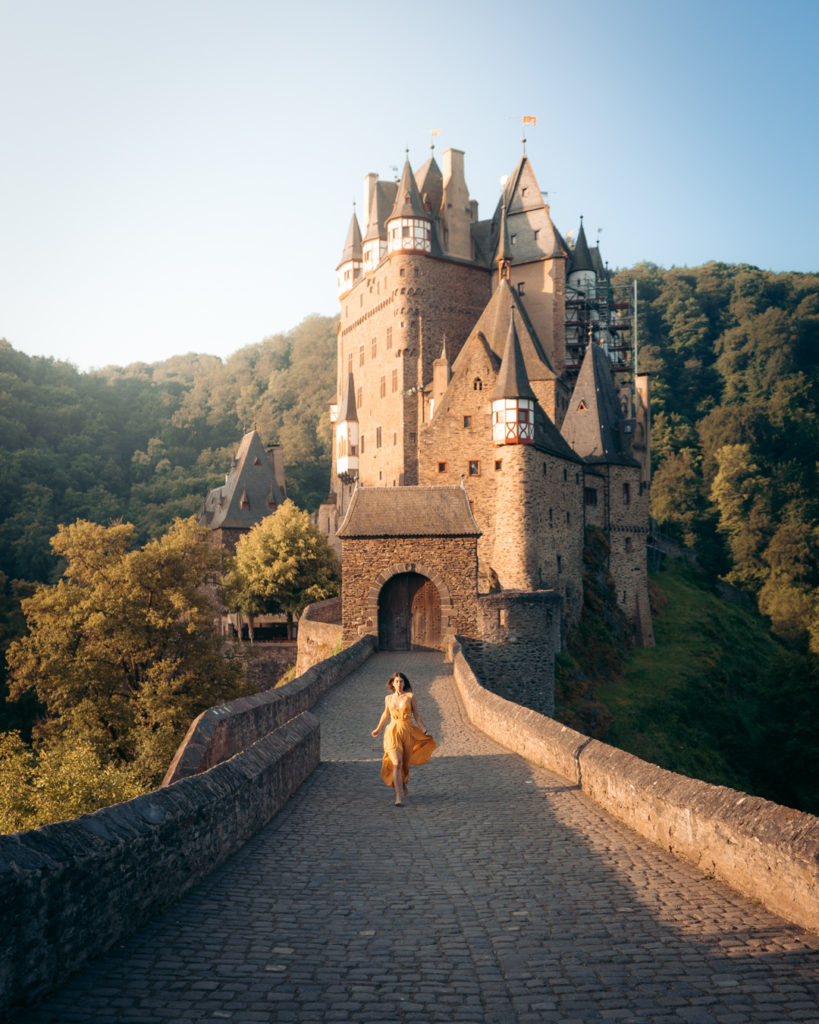 girl in a yellow dress running in front of eltz castle germany