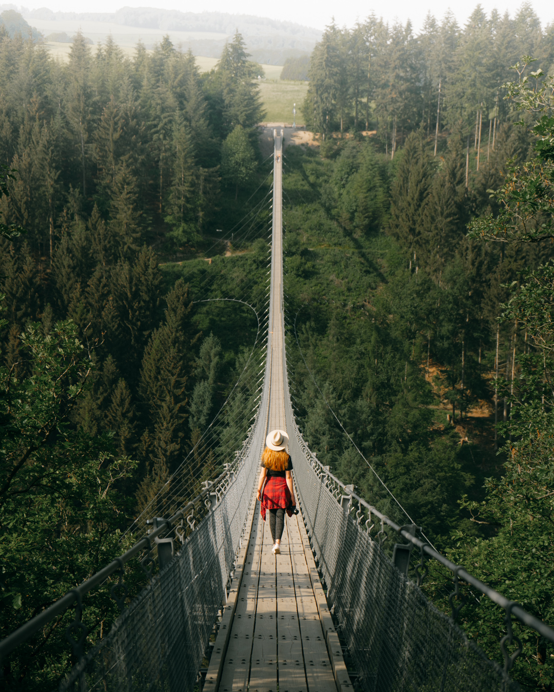 girl in a hat walking across Hangeseilbrukcke Geierlay germany bridge