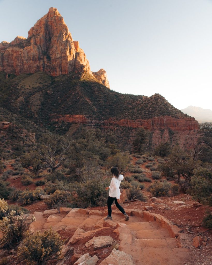 girl walking the watchman trail at sunset in zion national park utah