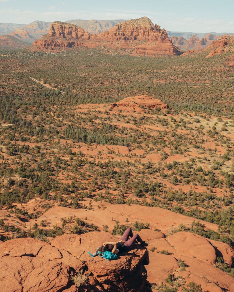 female hiker laying at the top of bell rock vortex climb on a sunny day in sedona az