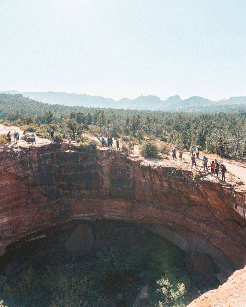 hikers looking at the devils kitchen sinkhole in sedona arizona
