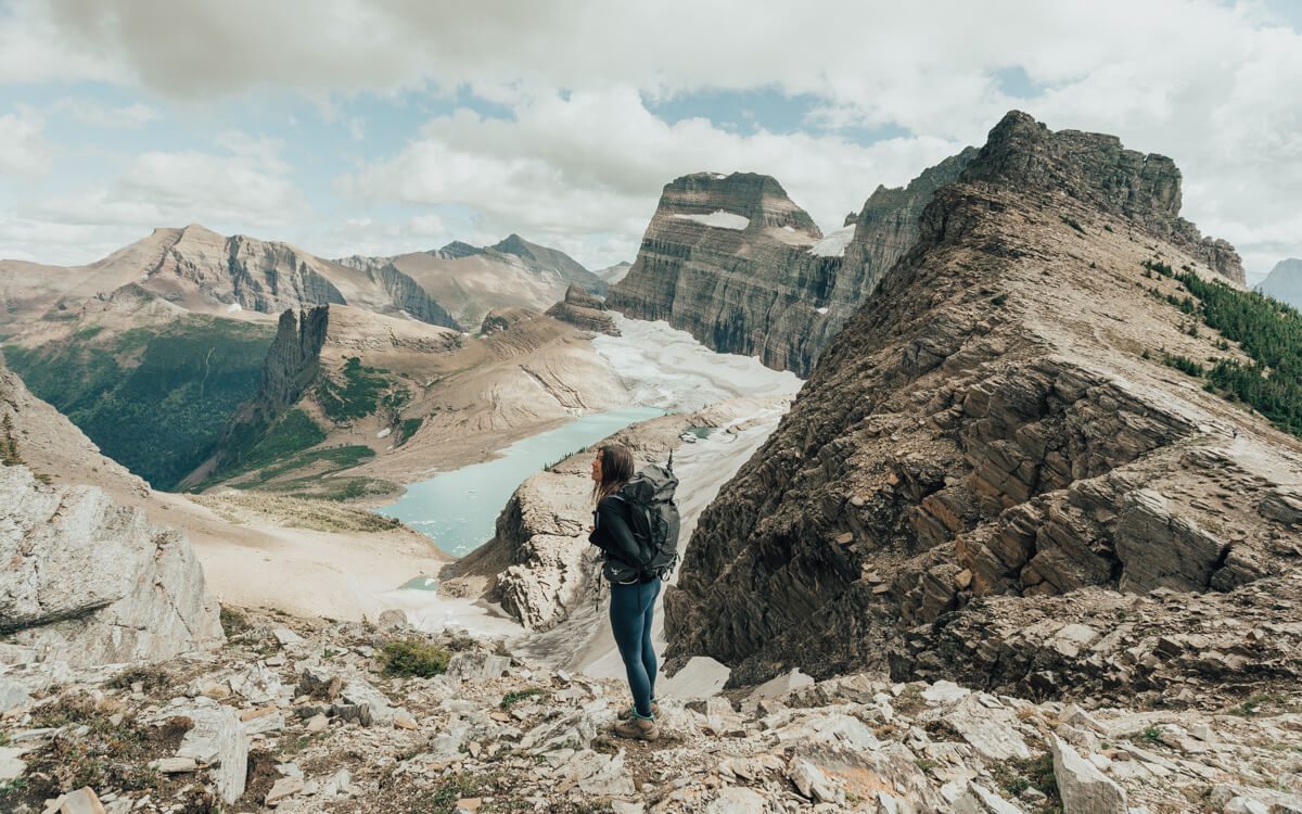 female hiker looking at the turquoise blue water from grinnell glacier overlook in glacier national park