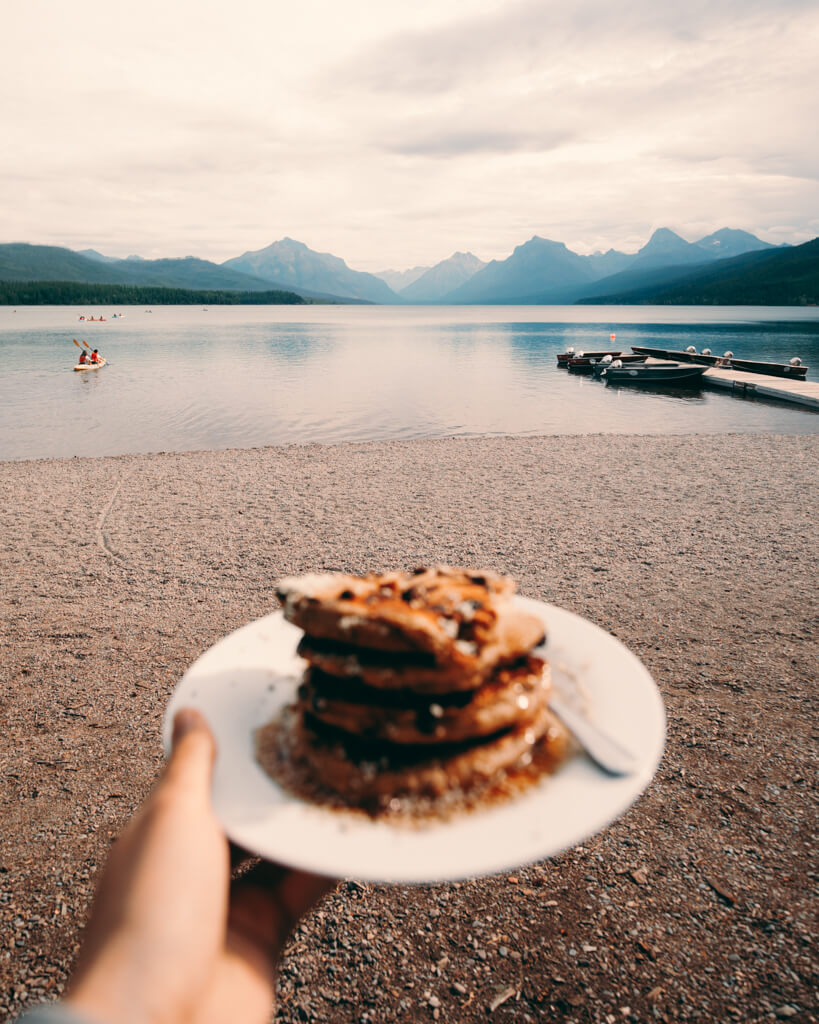 Girl holding pancakes on Lake McDonald shore during Sunrise in Glacier National Park