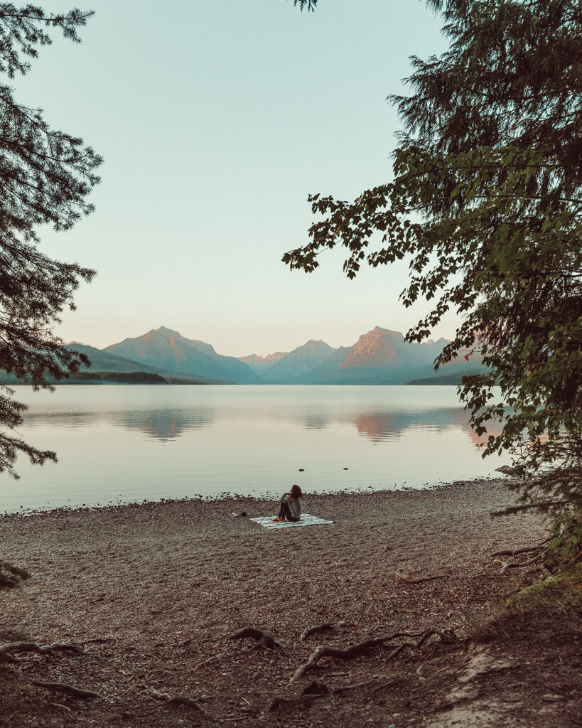 female sitting on a blanket watching the sunset over lake mcdonald in glacier national park montana