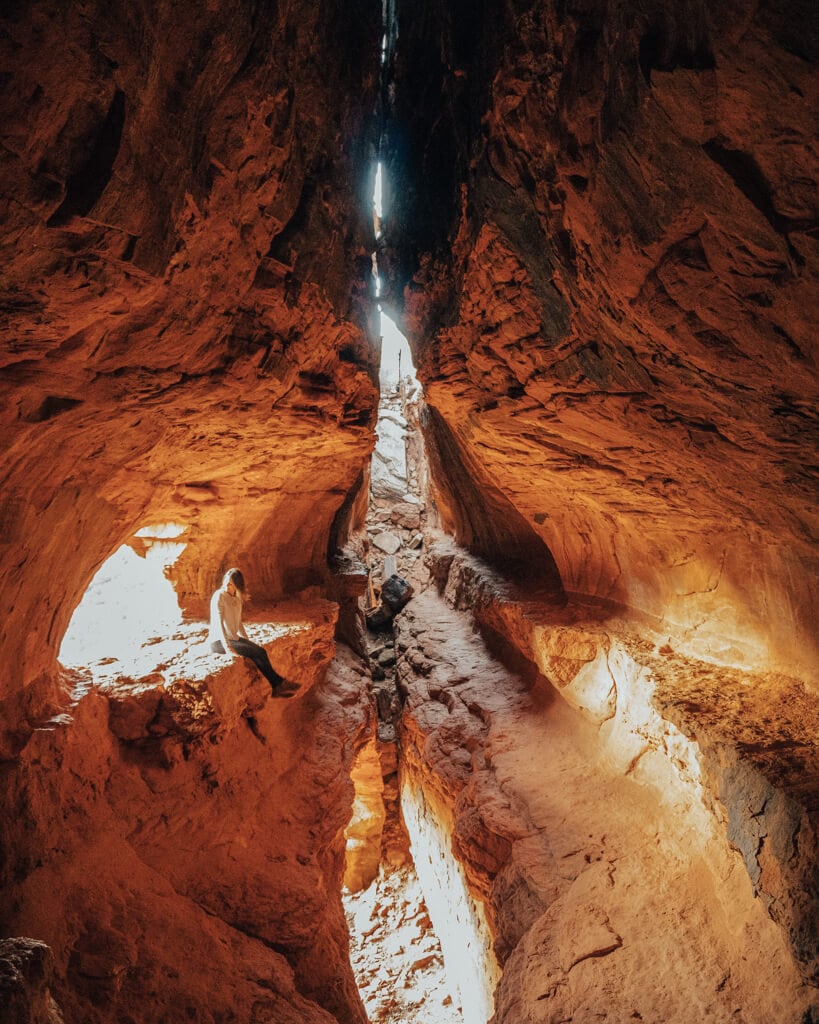 female hiker sitting in secret soldier pass cave in sedona arizona