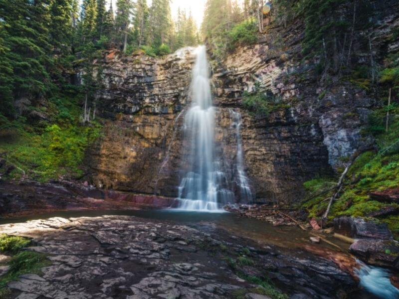 view of the double cascading virginia falls in glacier national park montana surrounded by greenery