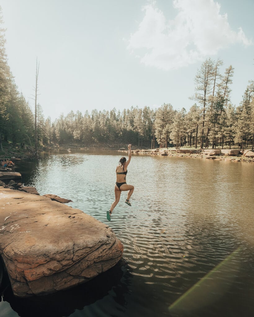 girl in a swimsuit jumping into knoll lake in payson arizona on a sunny day