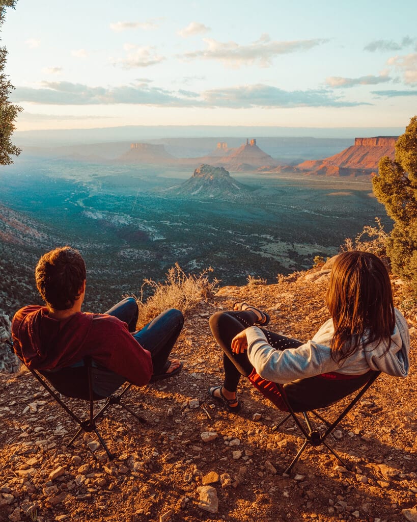 couple watching a pink unset over porcupine rim in moab uath