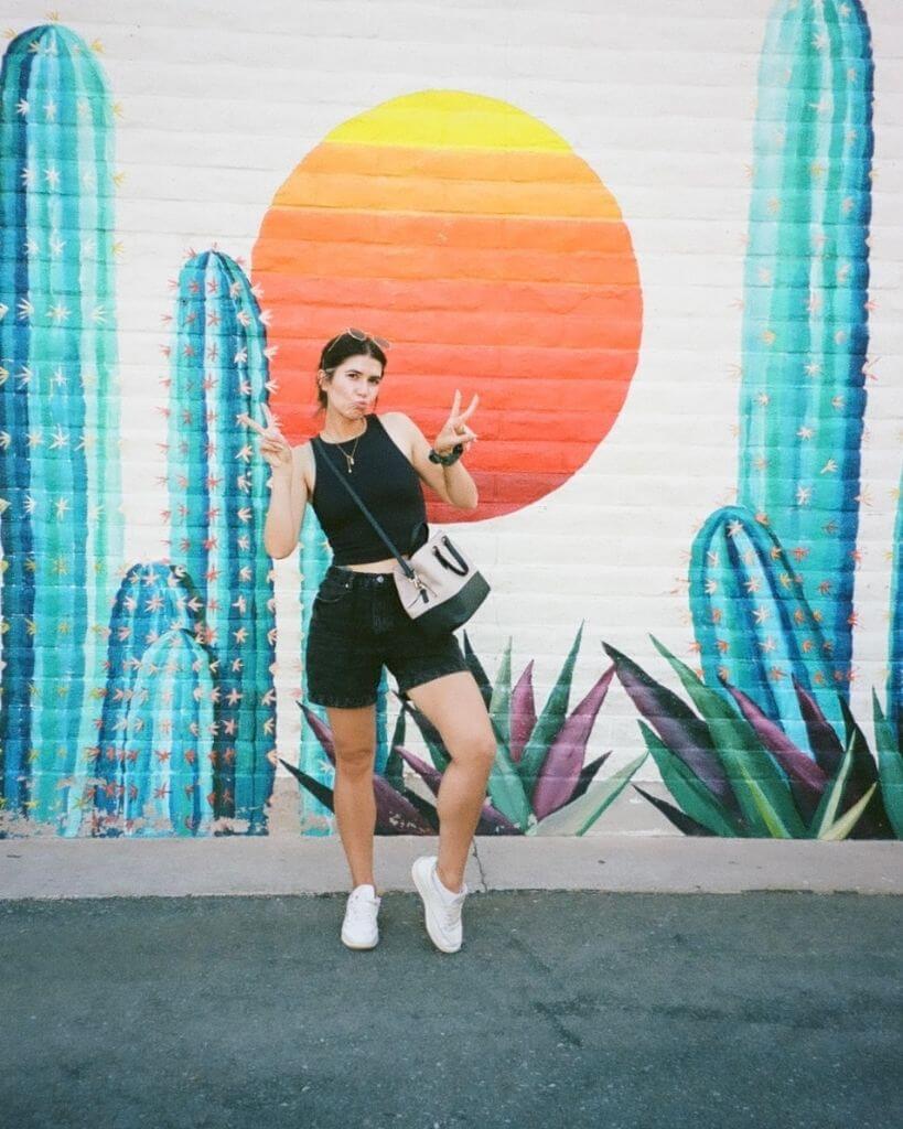 girl standing in front of the colorful its that hot mural scottsdale az