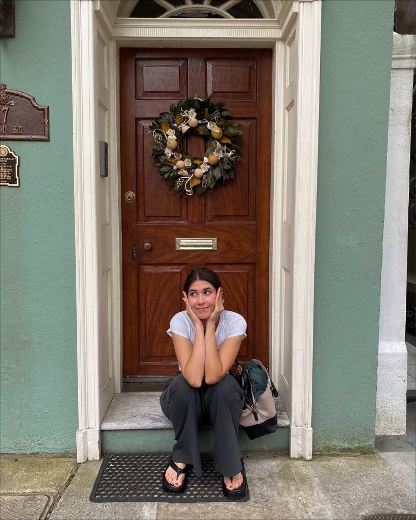 girl sitting in front of a home on rainbow row charleston