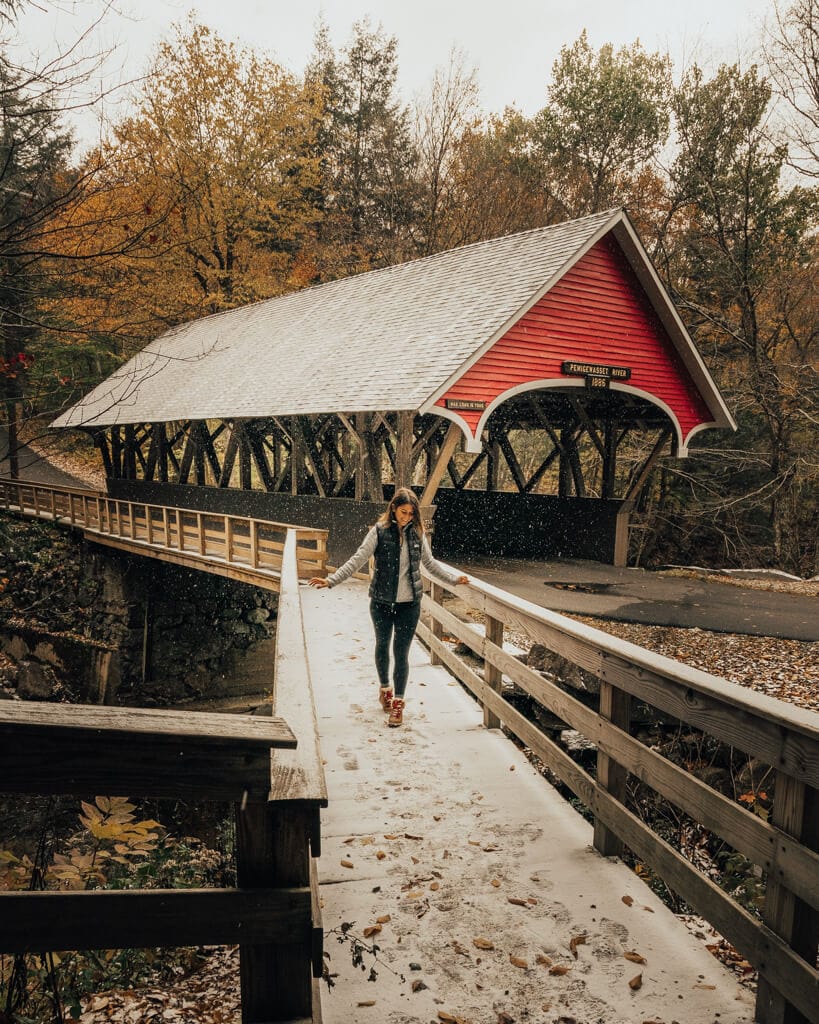 female walking near the red covered bridge in new hampshire white mountains flume gorge in the fall