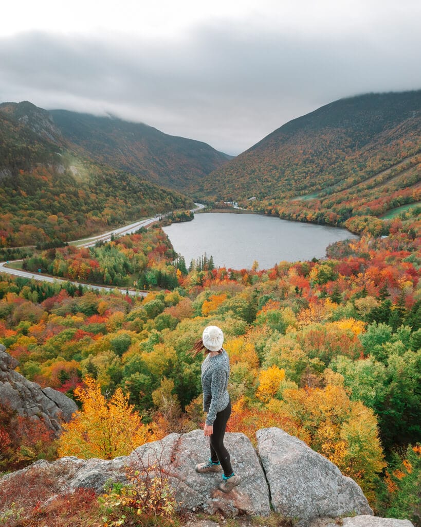 female hiker looking at fall colors on artist bluff in white mountains new hampshire