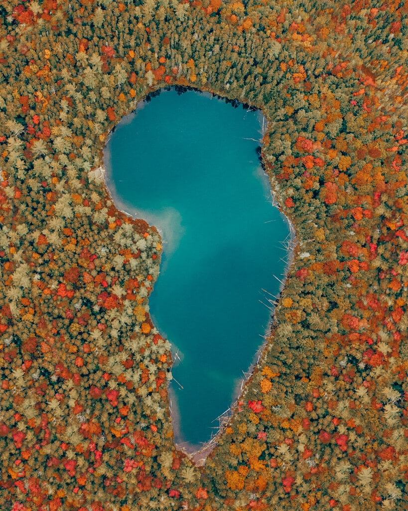 aerial view of falls pond surrounded by red and orange fall colors along kancamagus highway nh