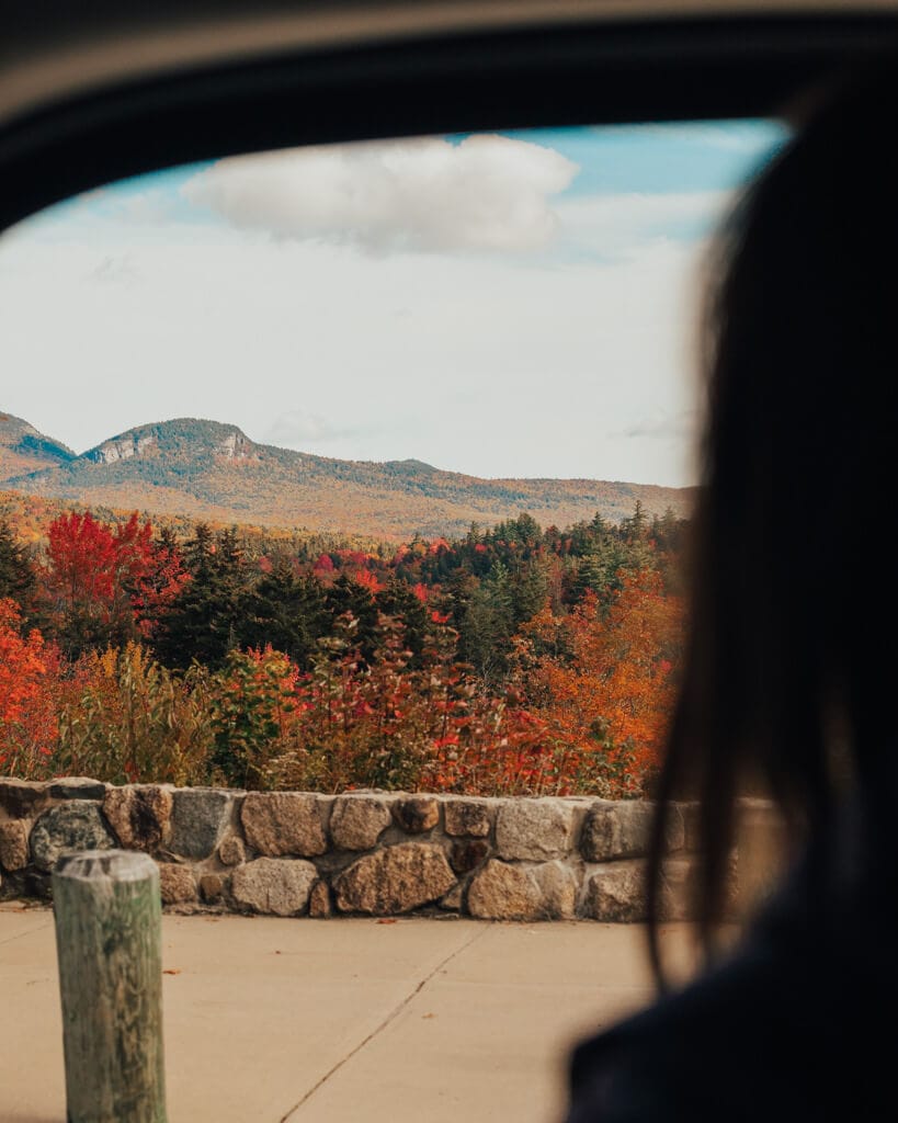 girl looking out a car window admiring sugar hill overlook in fall on the kancamagus highway nh