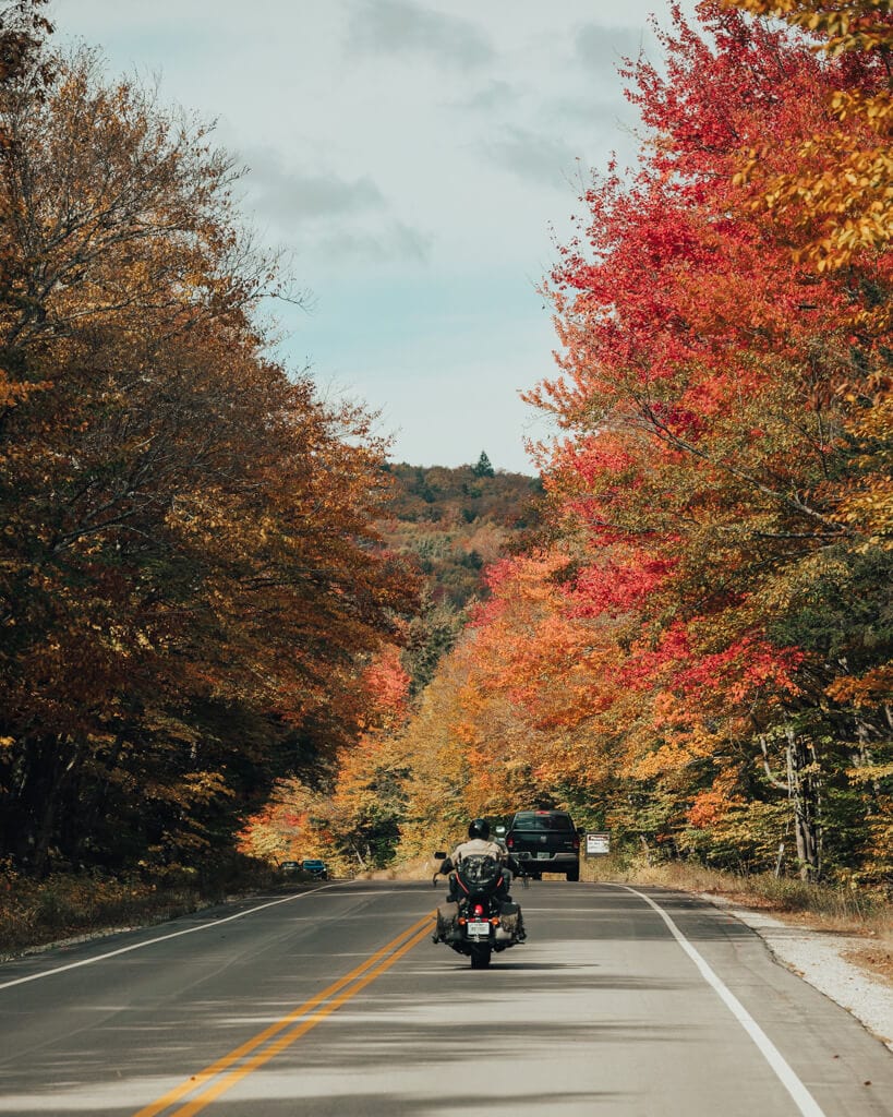 motorcycle driving through fall colors along the kancamagus highway nh