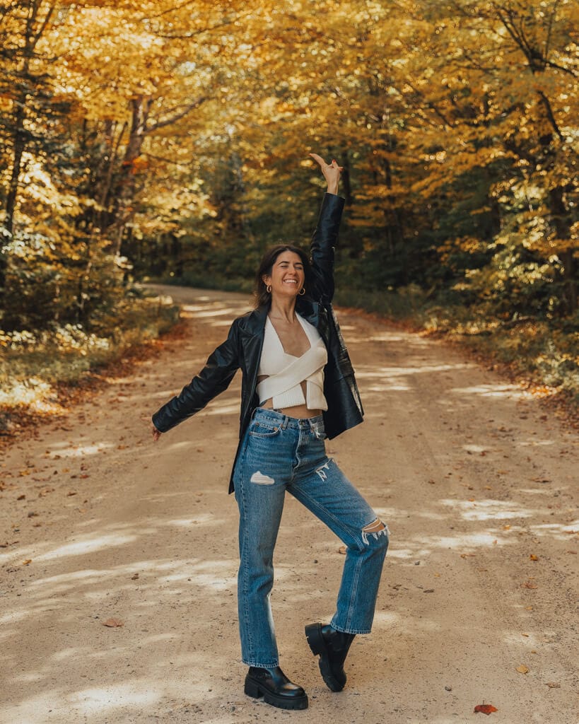 girl standing in a road covered by new england fall foliage