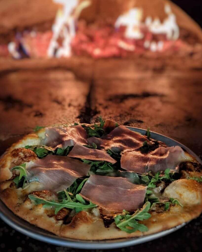 wood-fire pizza oven with a fresh pizza pie at the bench in stowe