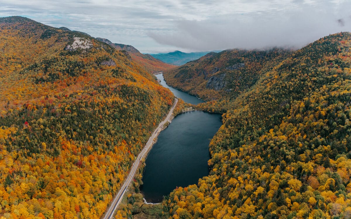 aerial view of fall foliage lining a scenic drive in new york's adirondack mountains