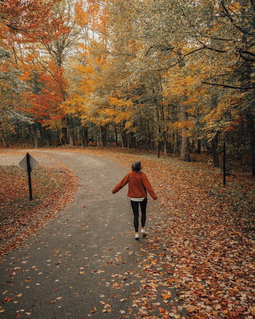 girl walking through the adirondack mountains through fall foliage