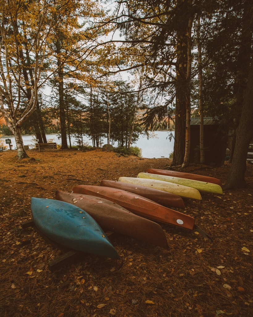 blue, yellow, and red canoes at the adirondack loj with fall foliage everywhere