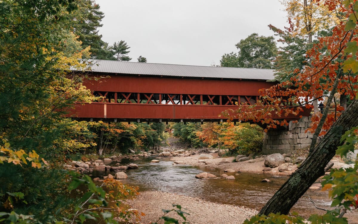 view of the red albany covered bridge along the kancamagus highway nh with fall foliage
