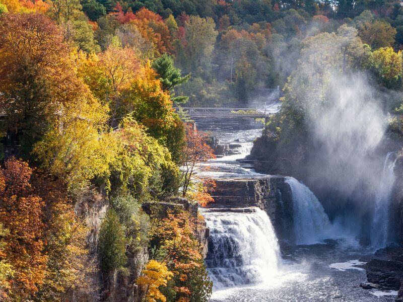 view of the ausable chasm waterfall in the adirondack mountains surrounded by fall foliage