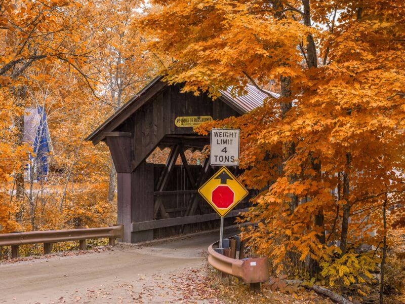 wooden covered bridge surrounded by fall foliage near stowe, vermont