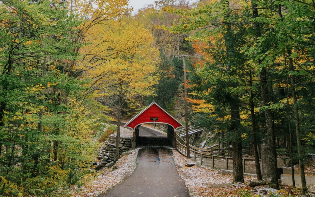 view of the red covered bridge in flume gorge along the kancamagus highway nh with fall colors