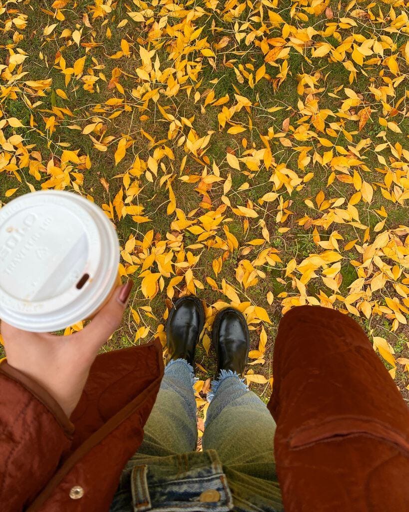 photo of a girl wearing fall boots looking at yellow fall foliage on the ground