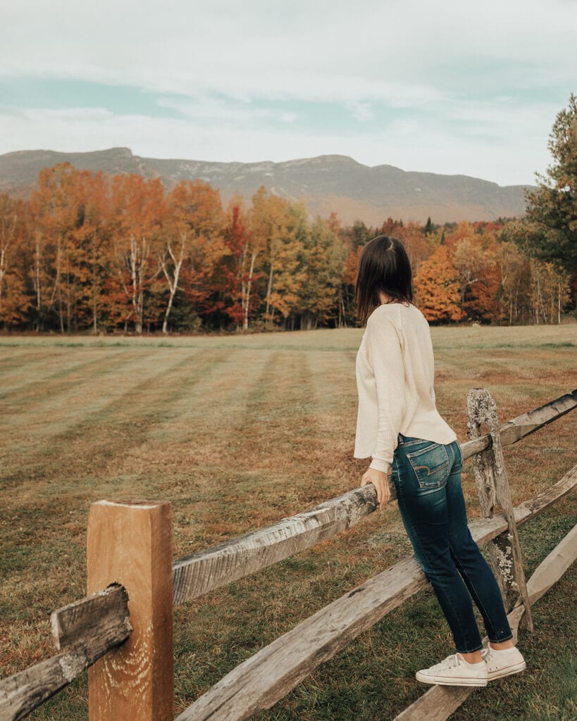 girl looking at the fall foliage in stowe, vermont with the mountains in the background