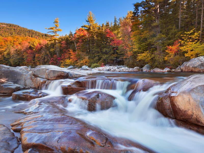 view of lower falls surrounded by orange fall foliage along the kancamagus highway nh