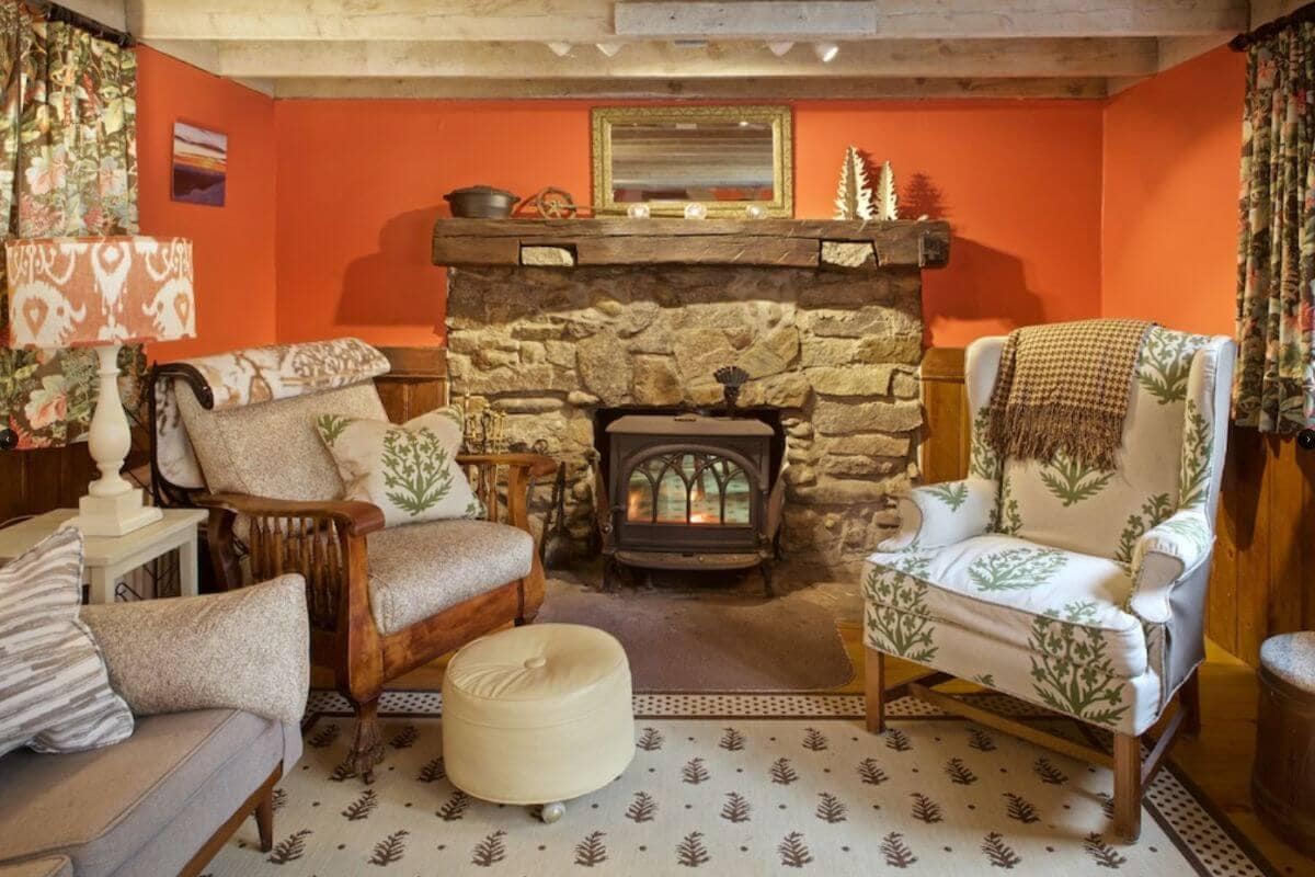 inside a cabin with a fireplace and large white chairs in conway new hampshire