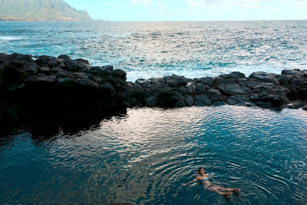 Girl floating in the blue Queen's Bath Kauai Hawaii