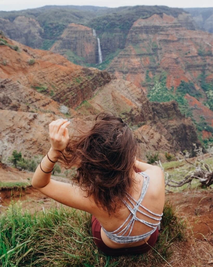 female hiker looking out at waimea canyon waterfalls in kauai hawaii