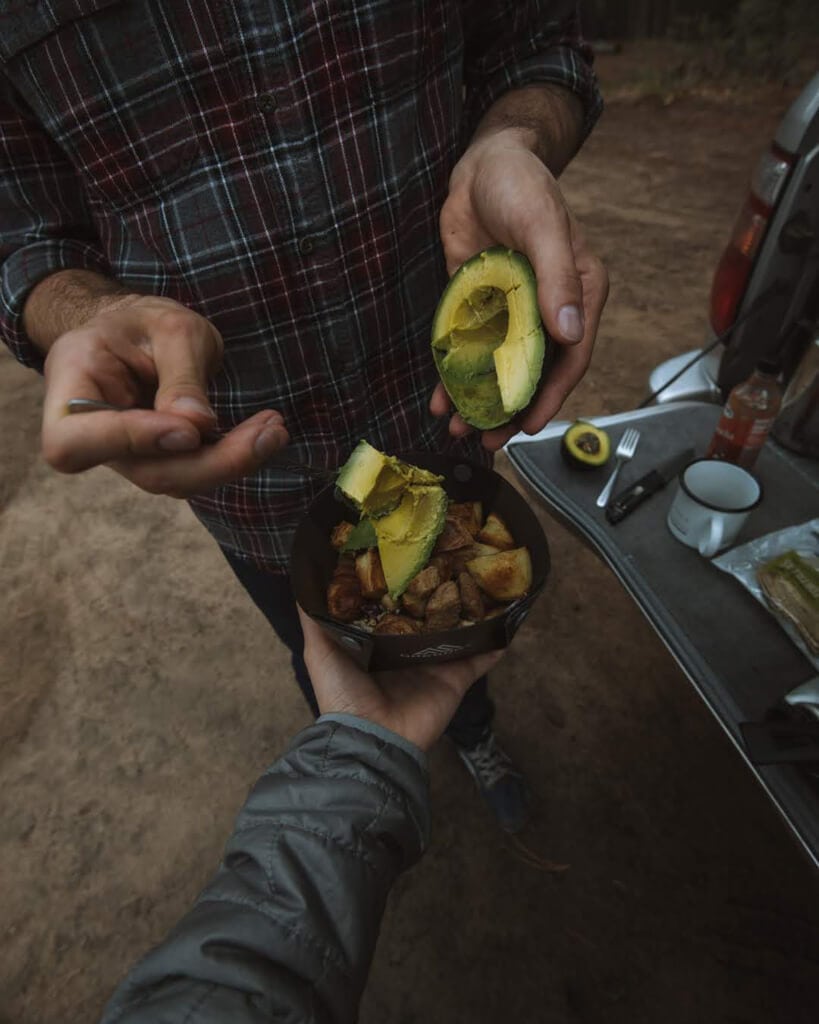 male and female eating avocado bowls while car camping
