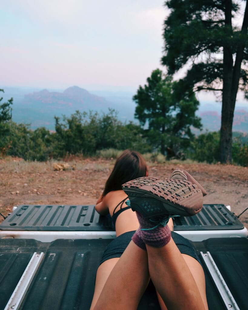 female camper watching the sunset from the back of a truck in east pocket arizona