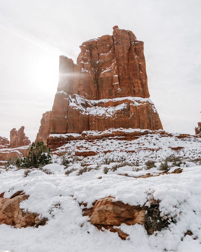 arches national park orange rock formation covered in winter snow