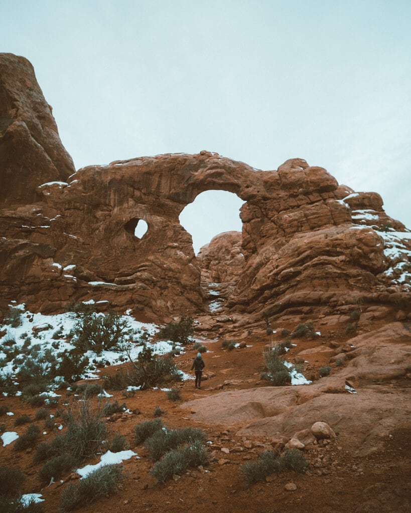 gloomy winter sunrise over turret arch in arches national park utah