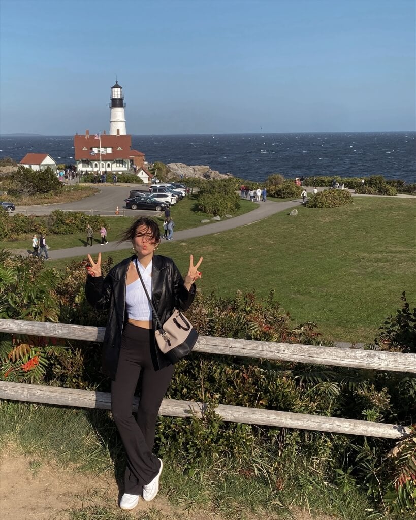 female standing in front of portland head light maine
