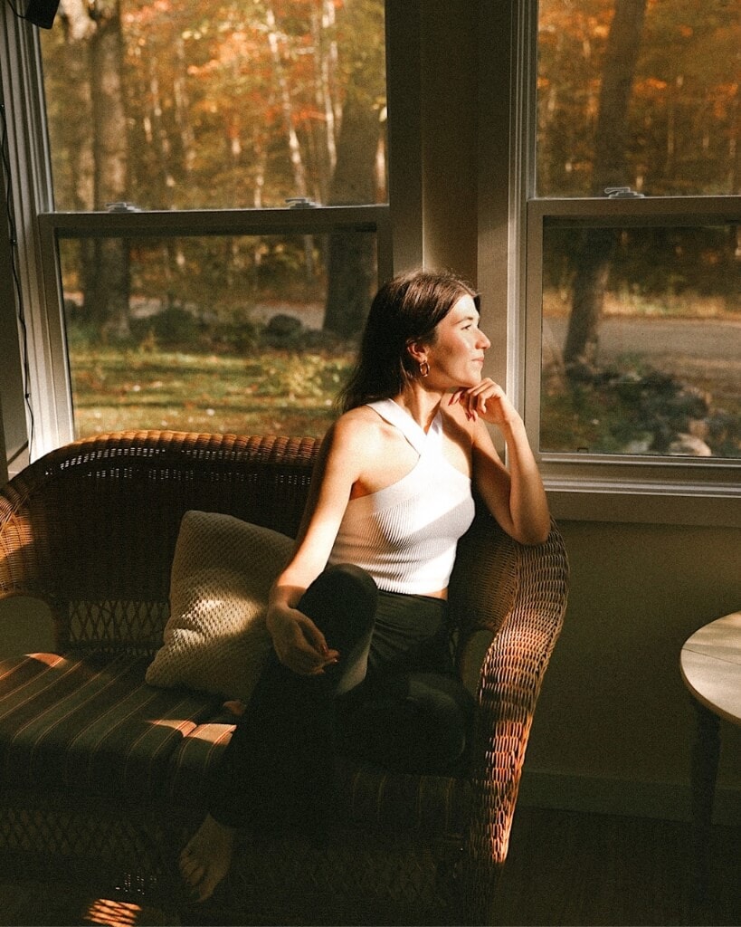 female sitting in a sun room in a cabin in maine during the fall