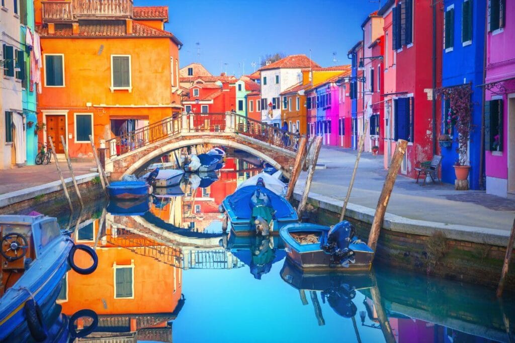 calm canal around colorful orange building of Burano Venice italy