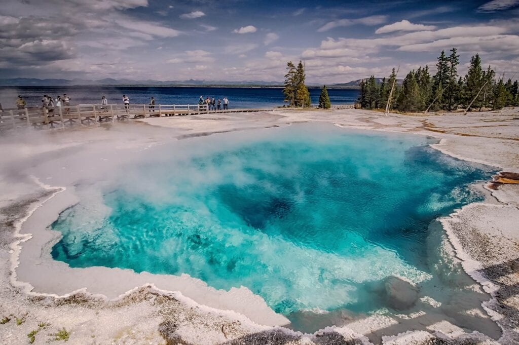 sunny day over the bright teal West Thumb Geyser Basin in yellowstone national park